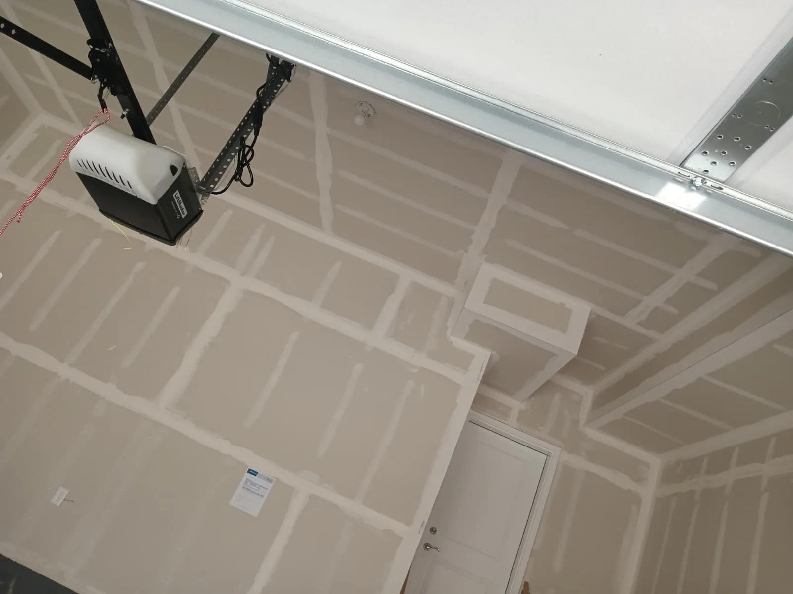 Garage ceiling and walls taped: seams, butt joints and screw lines coated straight around the opener rail and door track.