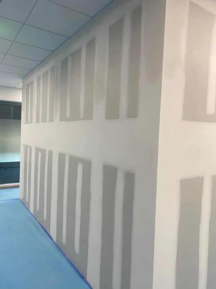 Interior partition wall taped and sanded, floor papered and base taped off before finishing continues.